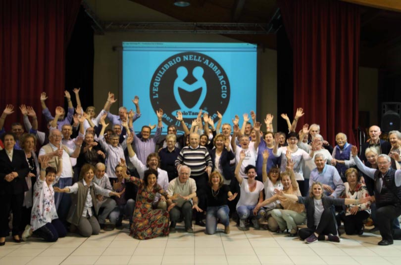 gruppo persone con dietro poster equilibrio abbraccio